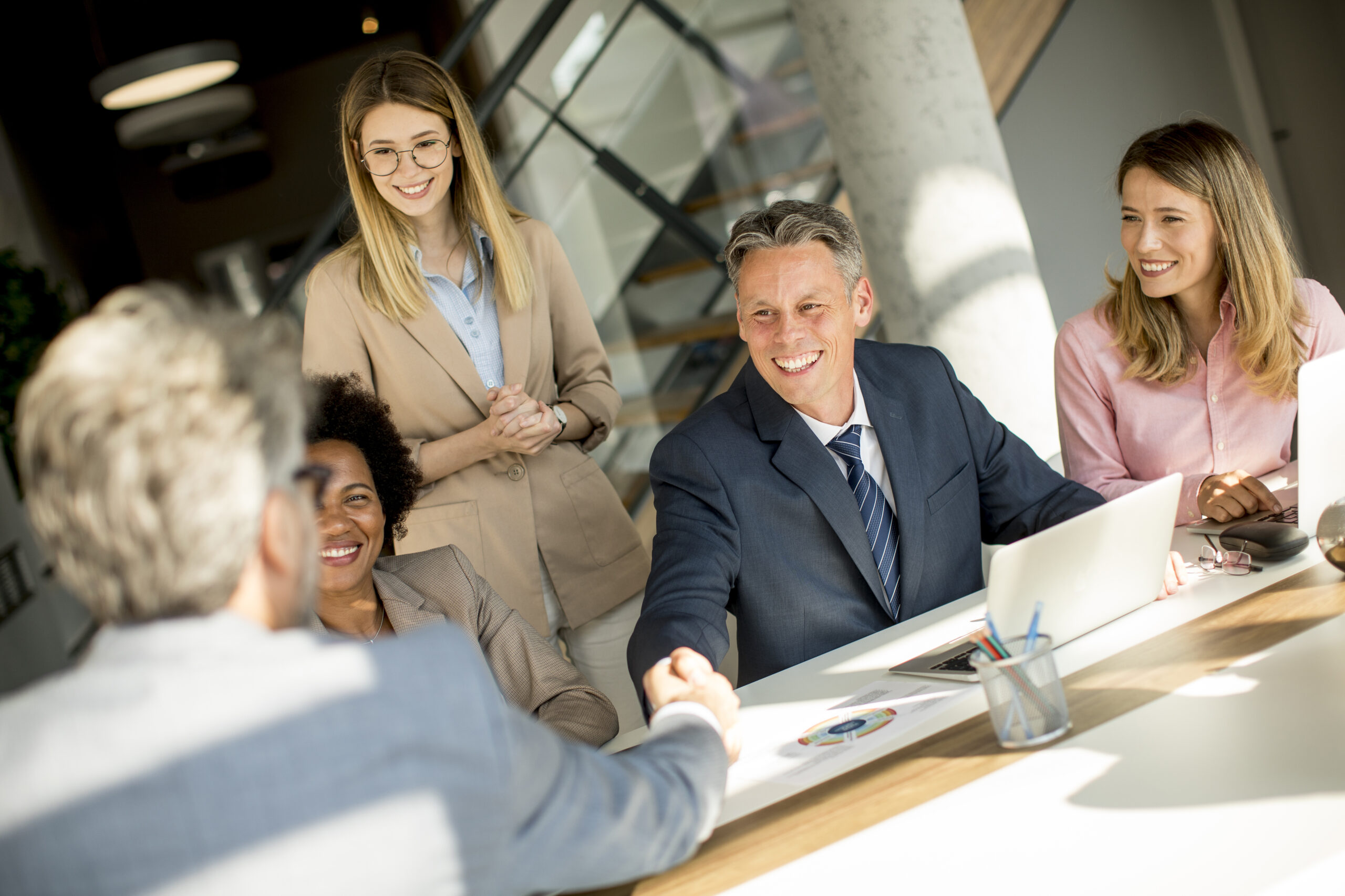 Business people shaking hands while sitting by the desk in the office